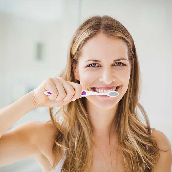 A woman in Paradise Valley, AZ, gently brushing her teeth for a thorough cleaning.