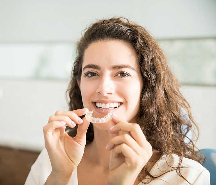 Beautiful Patient Holding Orthodontic Retainers In Dental Clinic