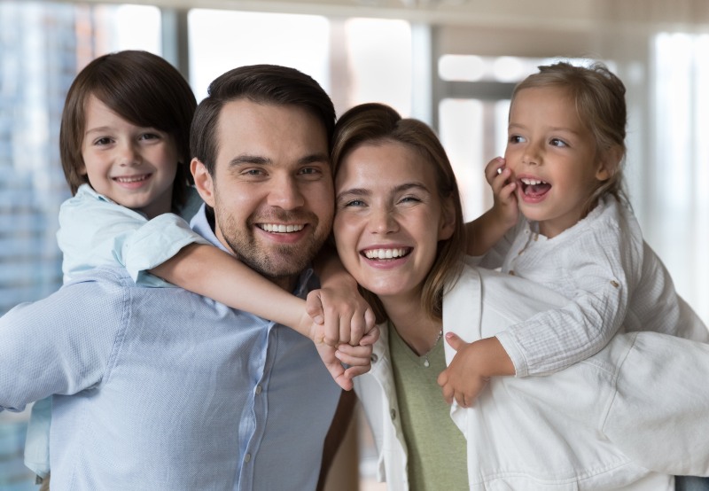 Happy Family of 4 smiling towards the camera - S&L Dental