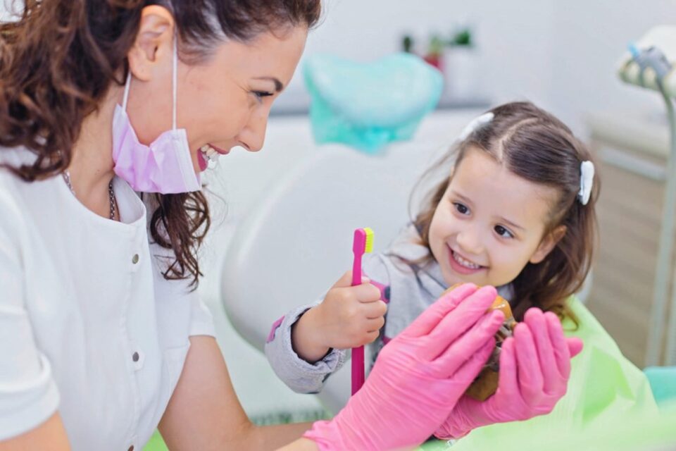 Dentist showing a child a toothbrush and model of teeth