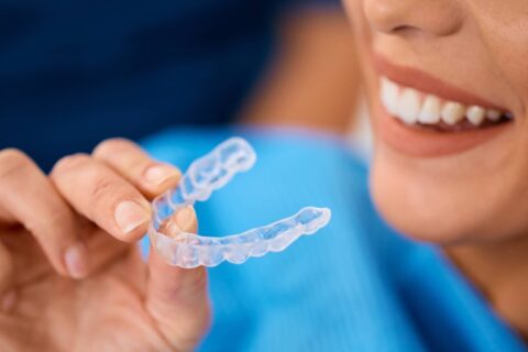 A close-up of a person holding a clear plastic retainer