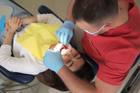 A dentist applies fluoride treatment to a patient