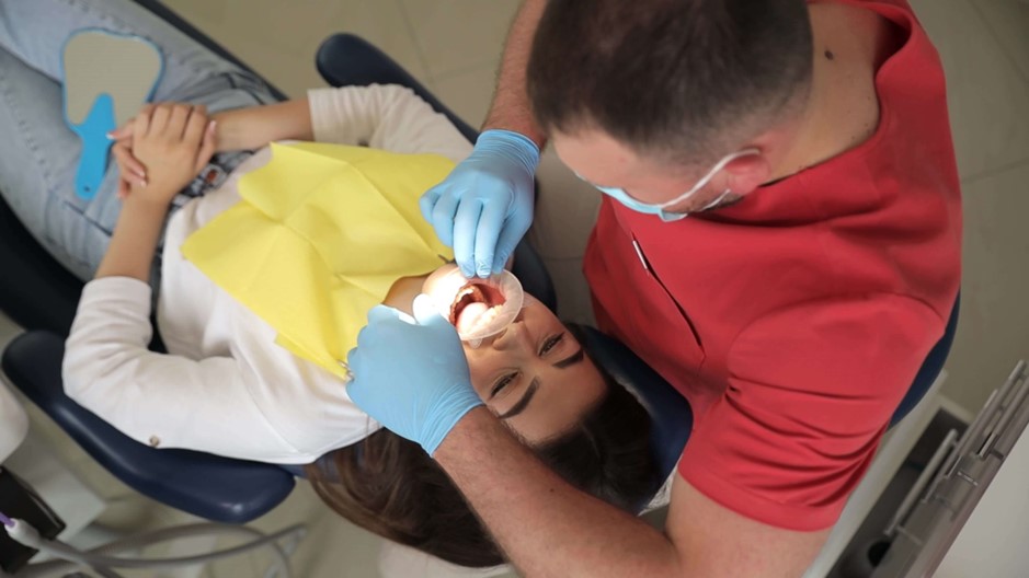 A dentist applies fluoride treatment to a patient