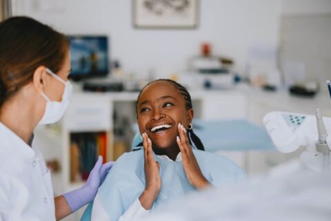 A person in a blue gown holding her face next to a dentist