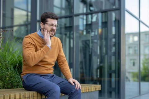 A person sitting on a bench with his hand on his cheek