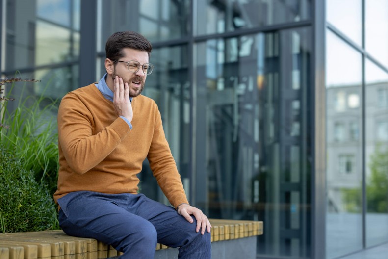 A person sitting on a bench with his hand on his cheek